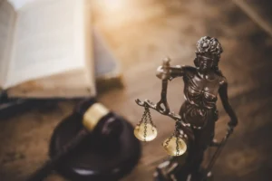 Estatua de la justicia sobre escritorio con documentos de registro de marca y patentes en México