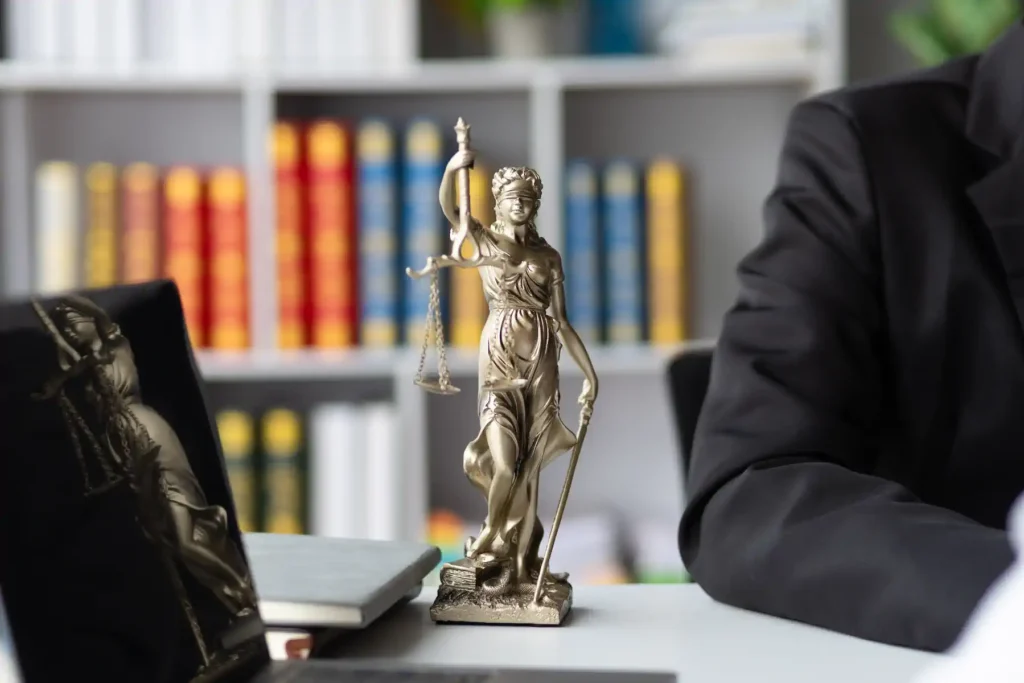 Estatua de la justicia junto a libros de derecho en despacho especializado en propiedad intelectual