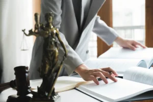 Abogado revisando documentos legales con estatua de la justicia