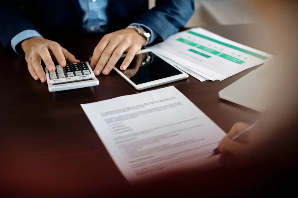 Professional using a calculator and tablet in a business meeting