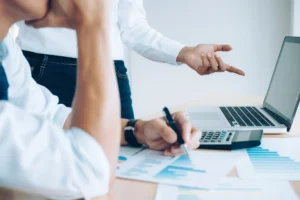 Dos personas analizando reportes financieros con laptop y calculadora