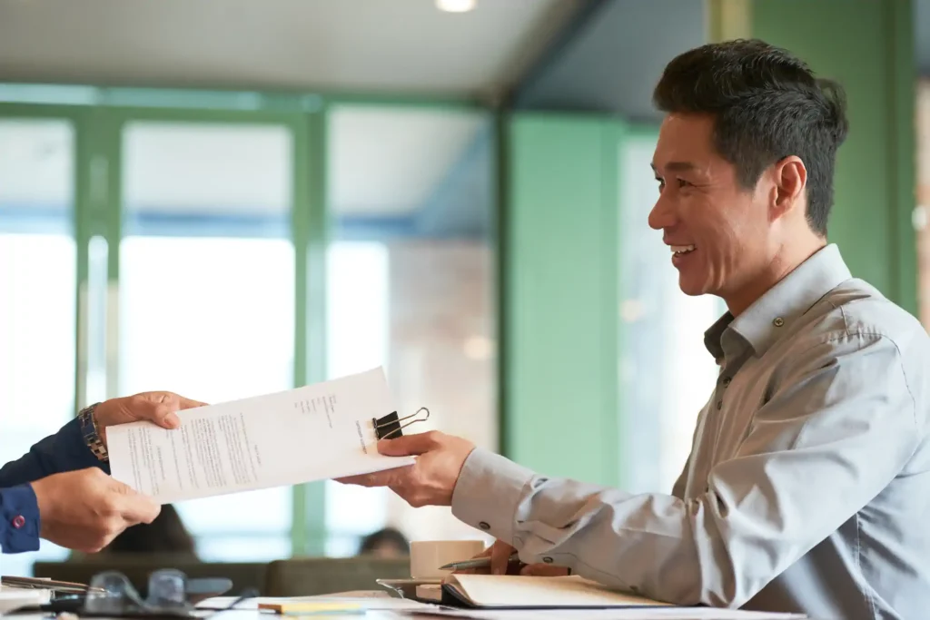 Smiling man receiving work documents in an office