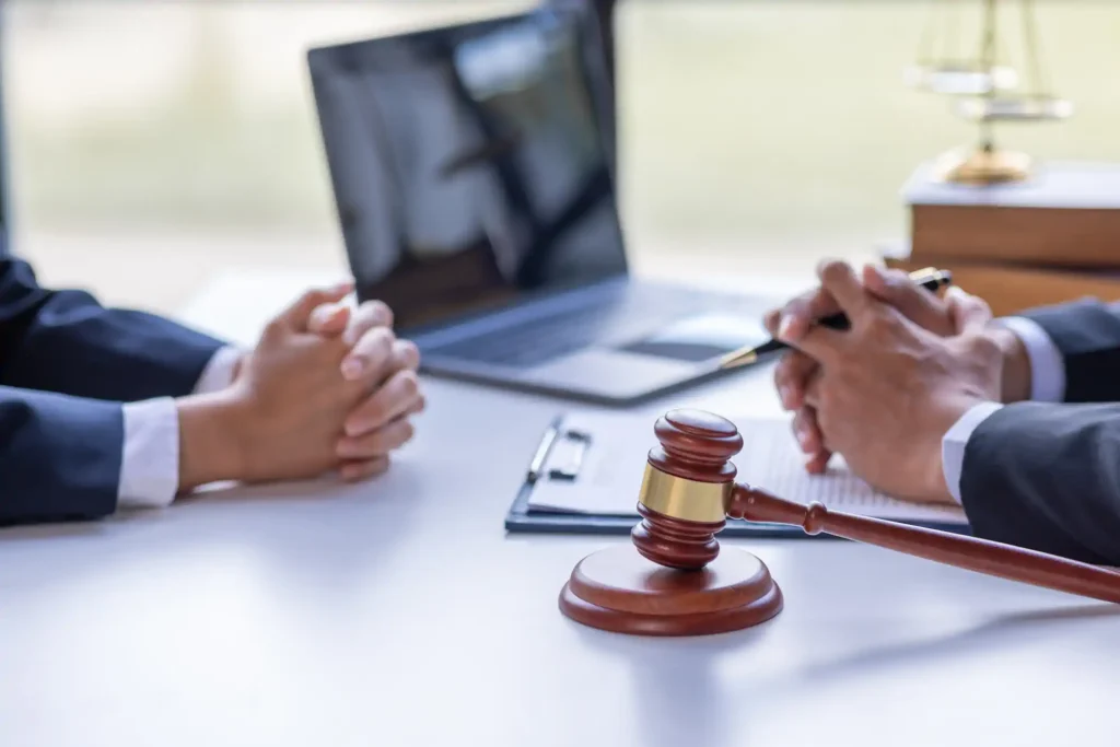 Dos abogados en reunión con mazo judicial sobre mesa