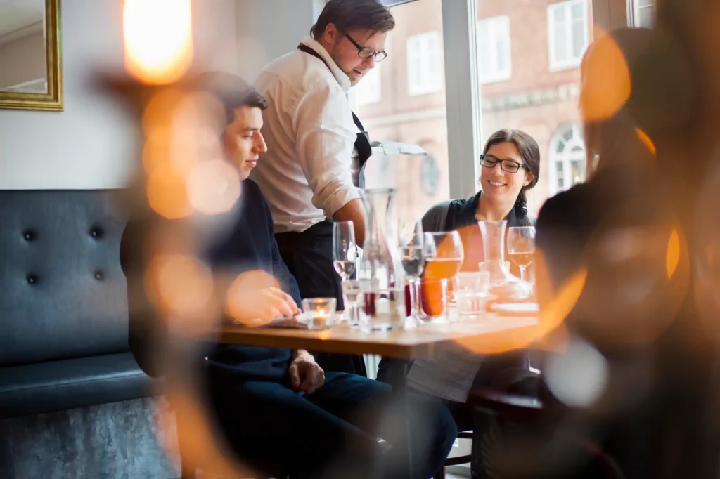 Mesero atendiendo a pareja en restaurante elegante