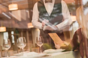 Mesero tomando orden a clienta en restaurante elegante