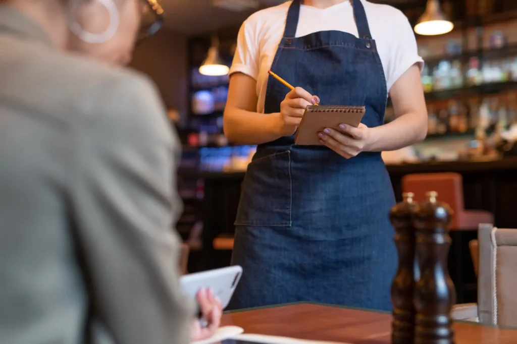Mesera tomando orden en restaurante con libreta y lápiz