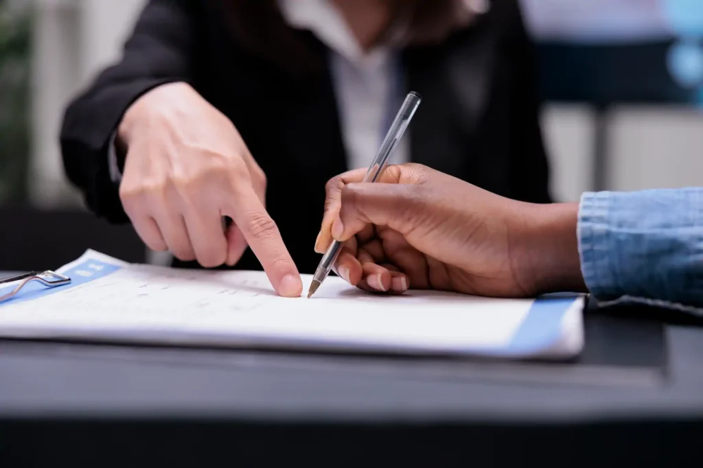 Dos personas firmando un documento en oficina