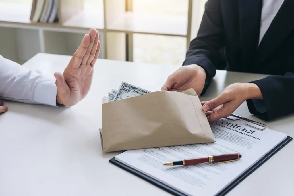 Persona rechazando soborno con dinero en sobre sobre contrato
