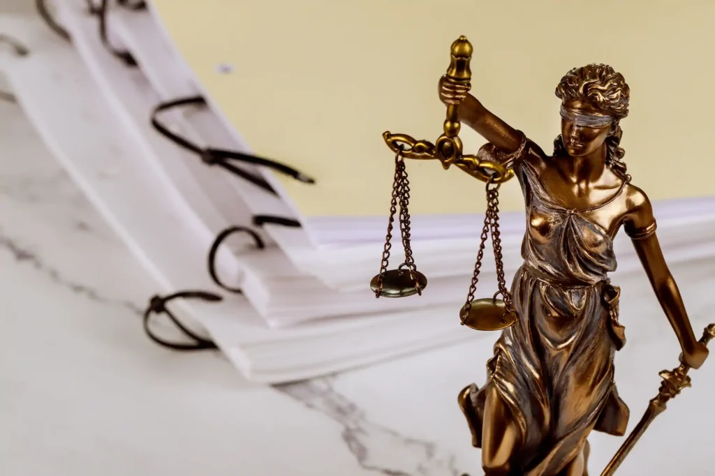 Estatua dorada de la Dama de la Justicia con documentos legales