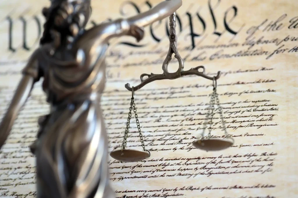Estatua de la Justicia con balanza sobre documento constitucional