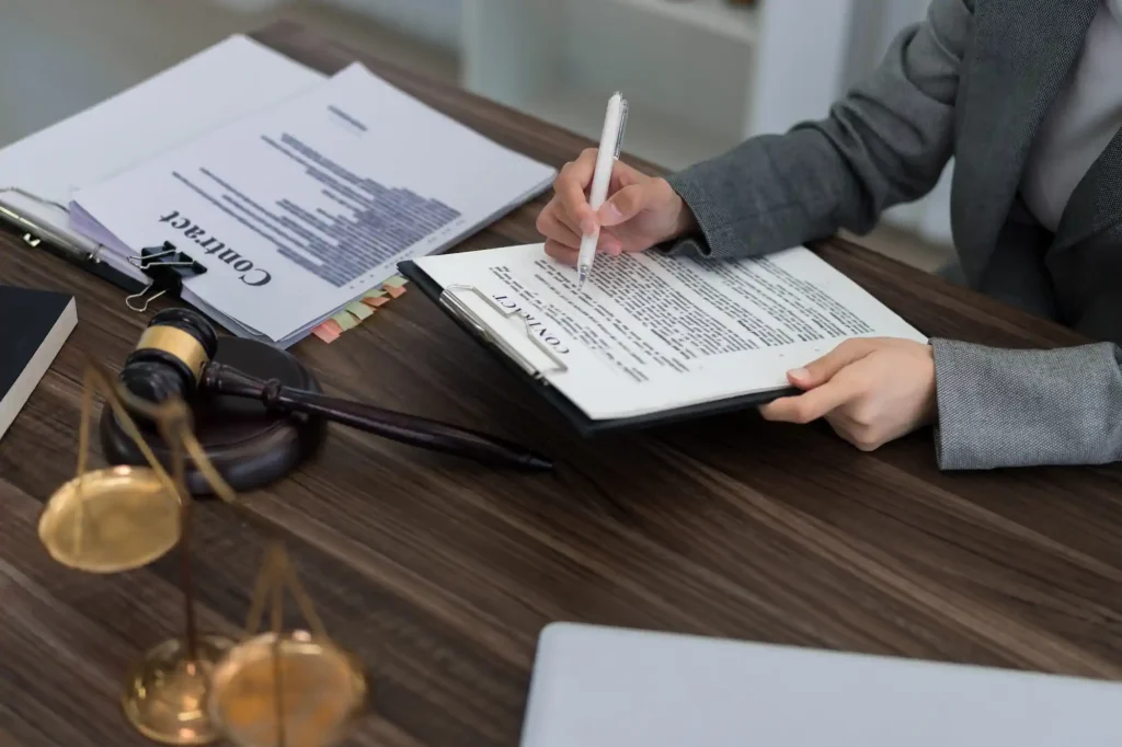 Attorney signing a legal contract with a gavel and scales of justice