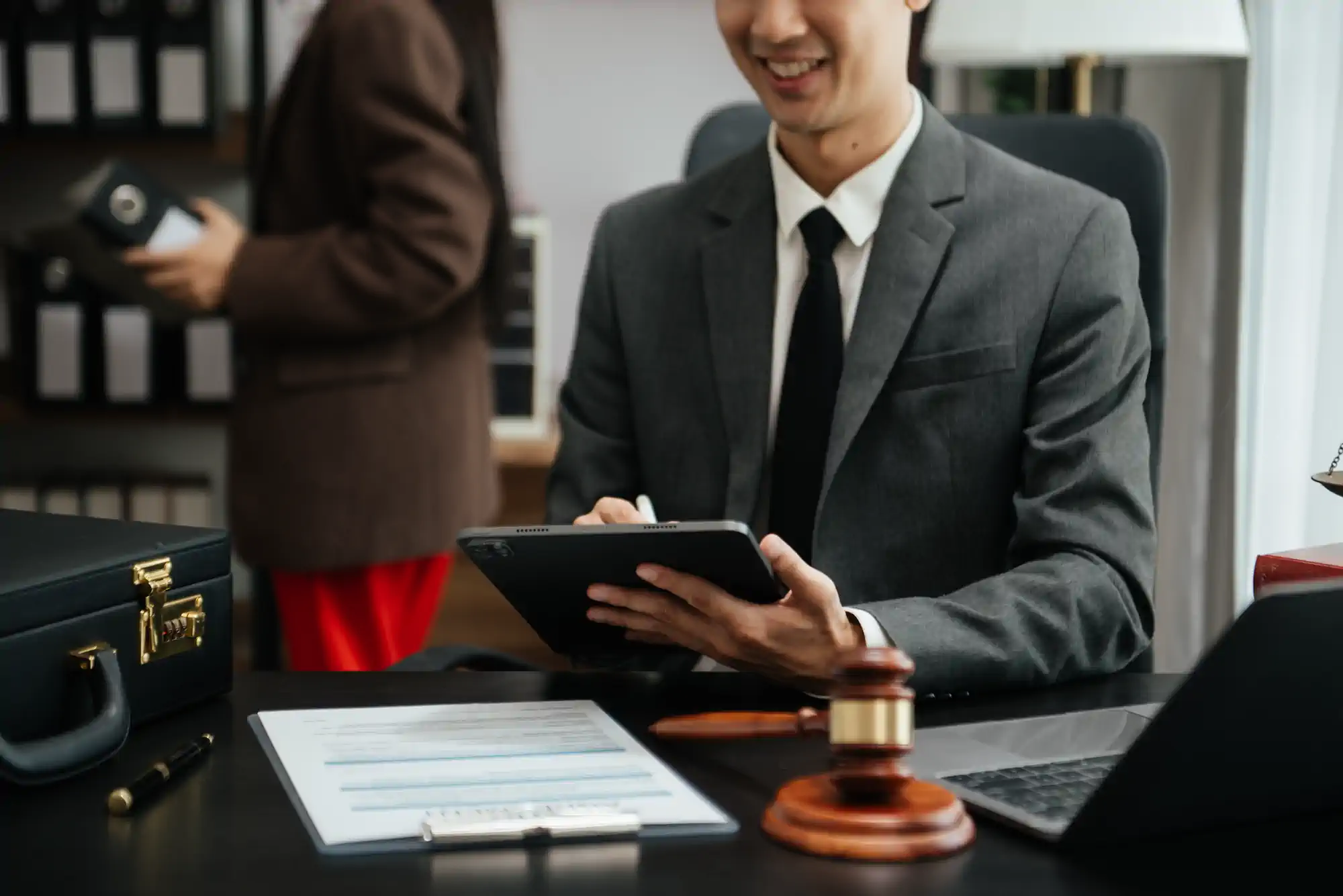 Abogado sonriente con tablet en escritorio con mazo judicial