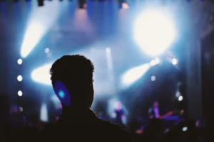Silueta de persona frente a escenario con luces de concierto